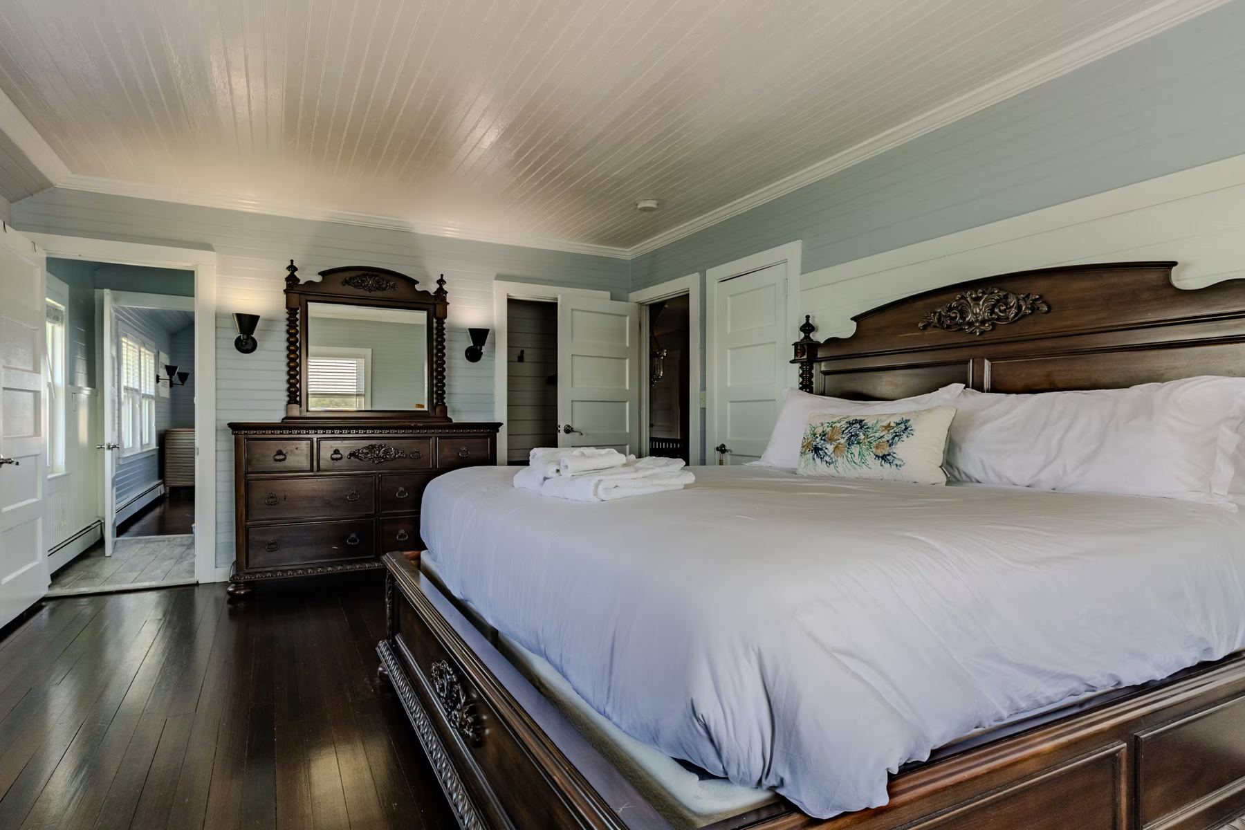 King bedroom with carved dark wood bed and white linen
