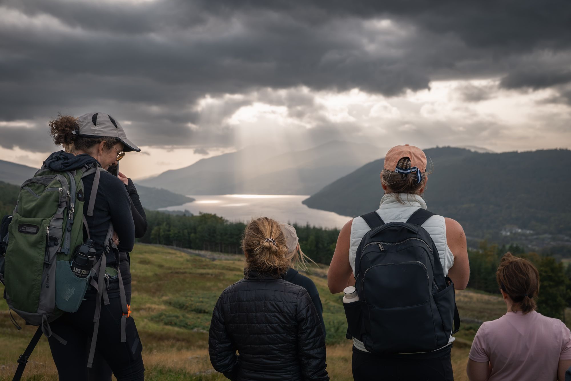Guests on the hill walk looking down Loch Tay as sunlight breaks through the clouds
