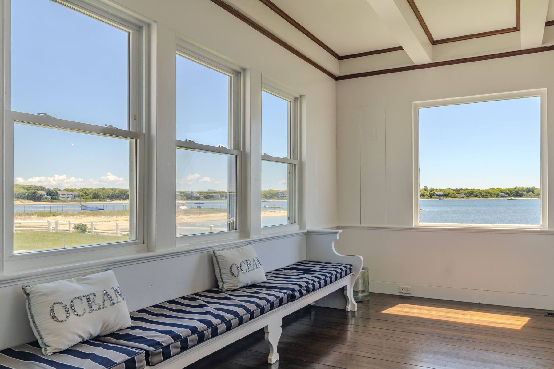 Sunroom with a long striped window seat looking out over Lewis Bay